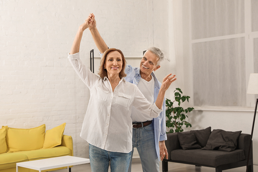 Happy senior couple dancing together in living room 